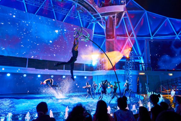 WN, Wonder of the Seas, AquaTheater, water show, night, performers, acrobatics, dancers, blue and purple, audience silhouette in foreground,